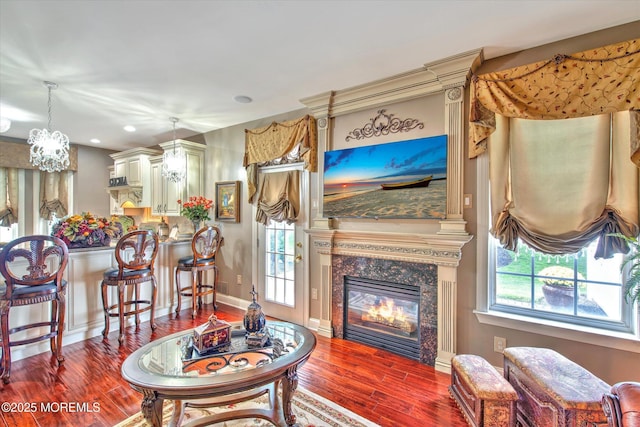 living room featuring an inviting chandelier, a high end fireplace, wood finished floors, and a healthy amount of sunlight