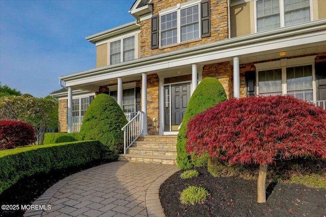 doorway to property featuring covered porch and stone siding