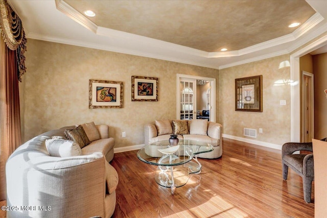 living area featuring a raised ceiling, baseboards, wood finished floors, and visible vents