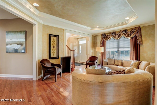 living area with baseboards, ornamental molding, and light wood-type flooring