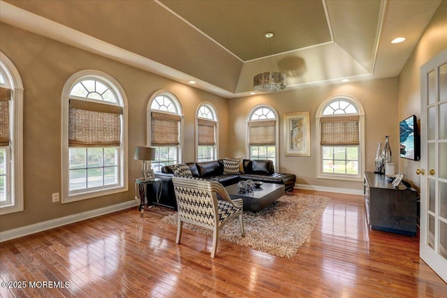 living room featuring wood-type flooring, recessed lighting, baseboards, and a tray ceiling