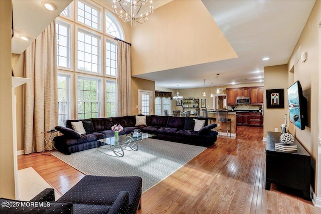living room featuring a towering ceiling, wood finished floors, and a chandelier