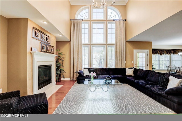 living room featuring plenty of natural light, a fireplace with flush hearth, a towering ceiling, and wood finished floors