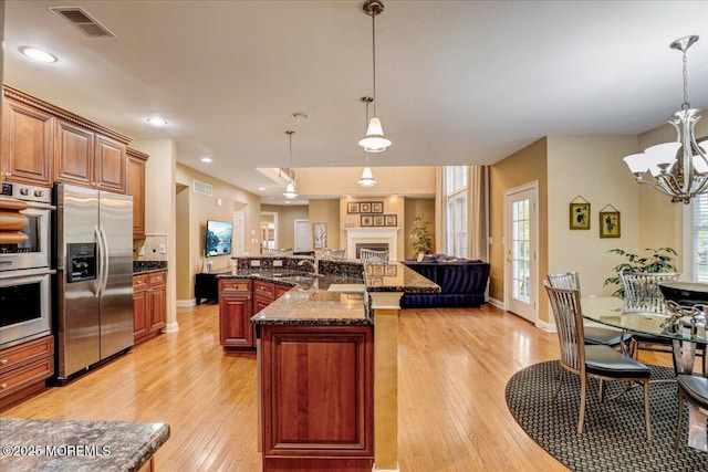 kitchen with visible vents, a notable chandelier, light wood-style floors, stainless steel appliances, and open floor plan