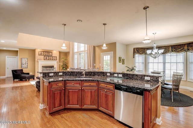 kitchen with a sink, hanging light fixtures, light wood finished floors, and dishwasher