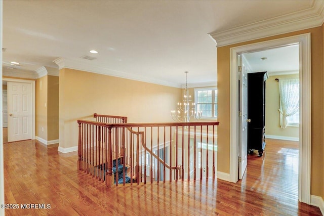 corridor with baseboards, a notable chandelier, wood finished floors, and an upstairs landing