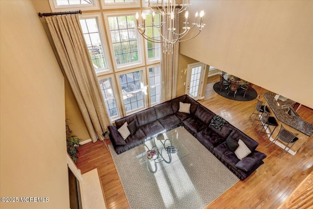 living area featuring a towering ceiling, a wealth of natural light, wood finished floors, and a chandelier