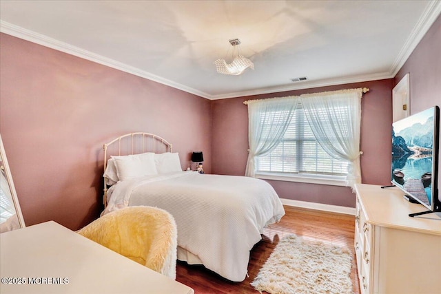 bedroom with crown molding, wood finished floors, and visible vents
