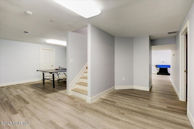 basement featuring visible vents, baseboards, stairway, and light wood-type flooring