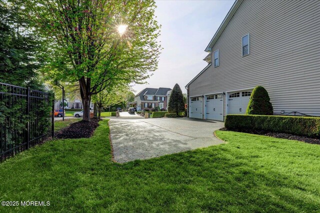 view of yard featuring an attached garage, fence, and driveway