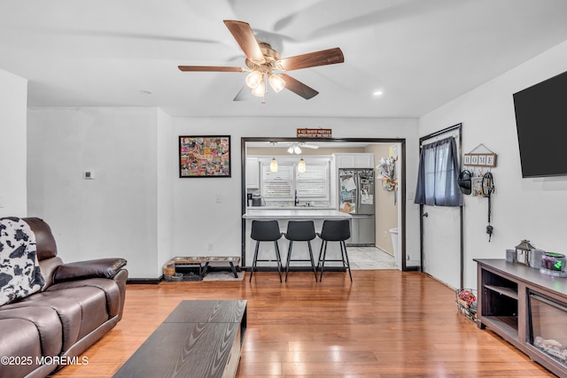 living room featuring baseboards, recessed lighting, ceiling fan, and light wood-style floors
