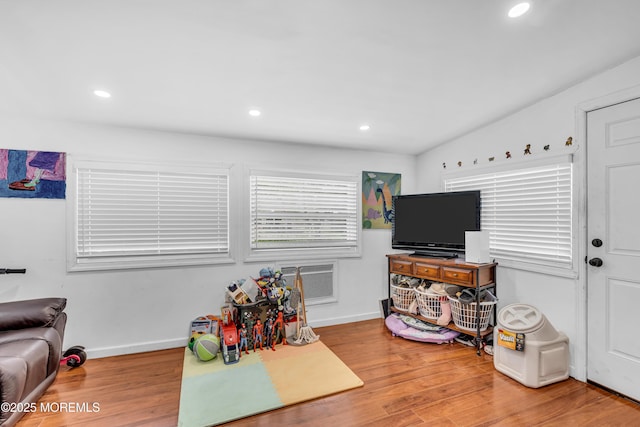 recreation room featuring recessed lighting, an AC wall unit, wood finished floors, and baseboards