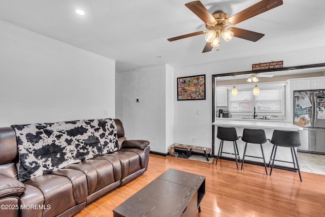 living area with ceiling fan, recessed lighting, baseboards, and light wood-style floors