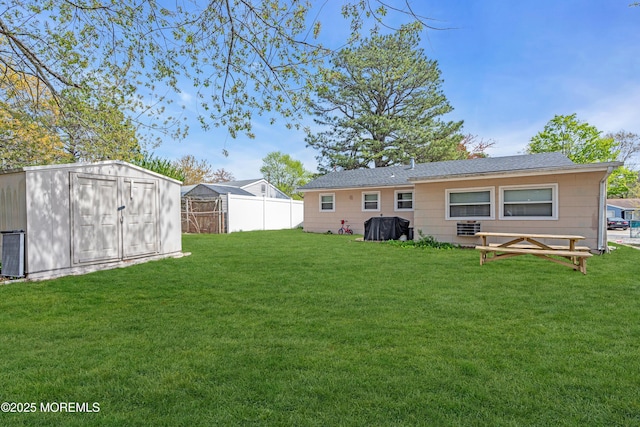 back of property with a lawn, fence, a shed, and an outbuilding