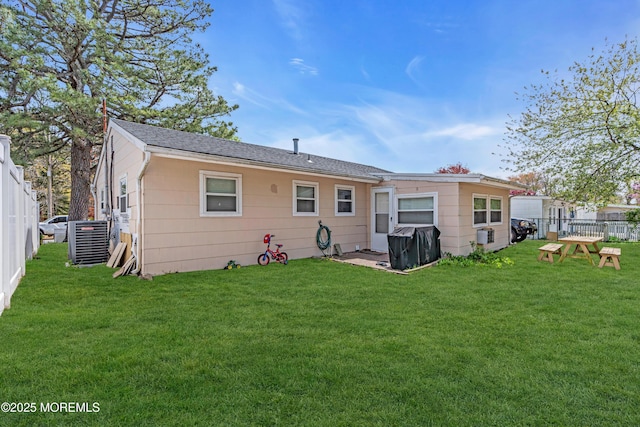 rear view of property with fence, cooling unit, and a yard