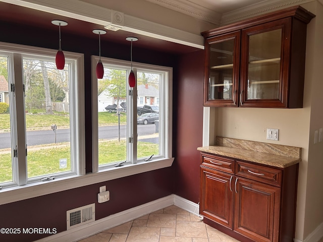 unfurnished dining area with visible vents, a healthy amount of sunlight, stone tile flooring, and baseboards