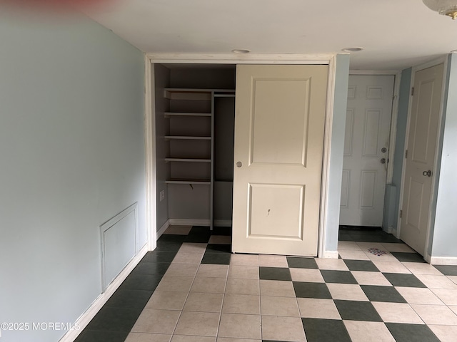 unfurnished bedroom with baseboards, light tile patterned floors, and a closet