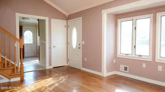 entryway with wood finished floors, crown molding, visible vents, baseboards, and lofted ceiling