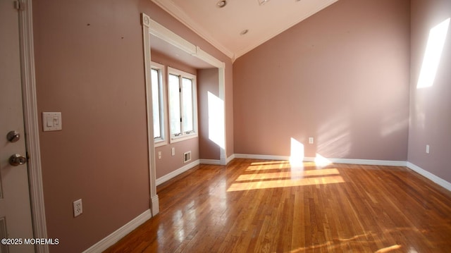 empty room with baseboards, visible vents, hardwood / wood-style flooring, and crown molding