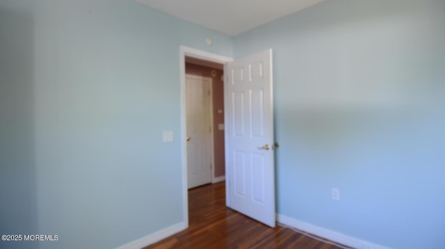 empty room featuring dark wood-style floors and baseboards