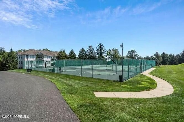 view of sport court with a lawn and fence
