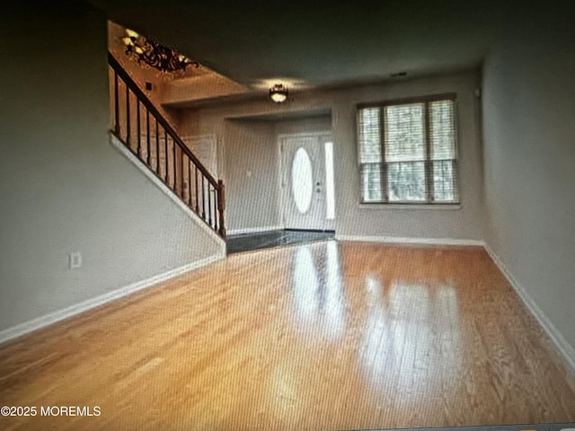 entryway with baseboards, wood finished floors, and stairs