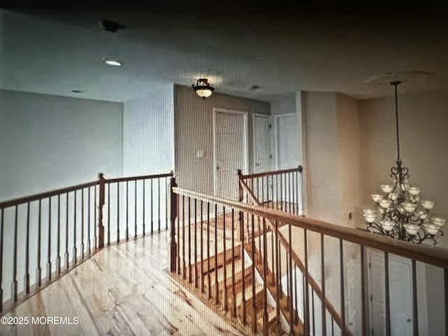 hallway featuring wood finished floors and a notable chandelier