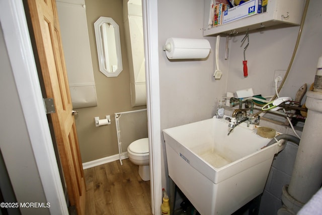 bathroom with wood finished floors, toilet, baseboards, and a sink