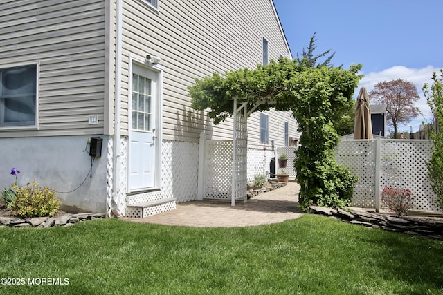 view of property exterior with fence, a patio area, and a lawn
