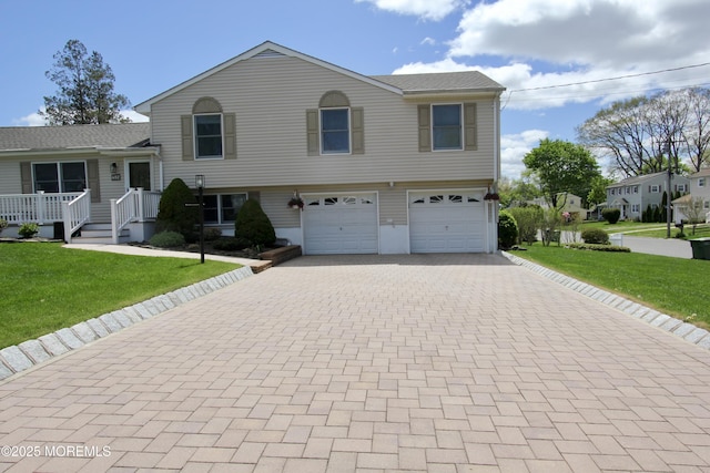 tri-level home featuring decorative driveway, a front yard, and an attached garage
