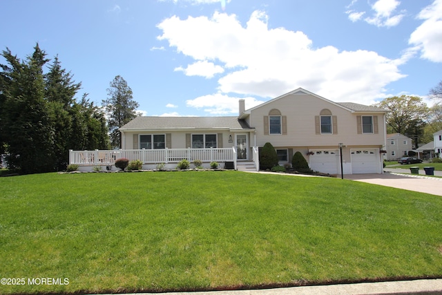 tri-level home with a porch, a front lawn, a chimney, concrete driveway, and an attached garage