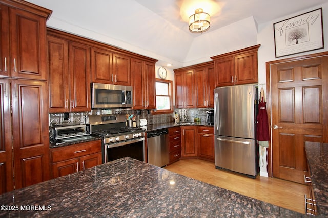 kitchen with decorative backsplash, a sink, stainless steel appliances, a toaster, and light wood-type flooring