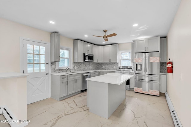kitchen featuring a baseboard heating unit, a wealth of natural light, appliances with stainless steel finishes, and decorative backsplash