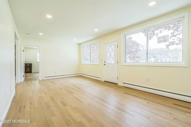 interior space with a baseboard radiator, light wood-style floors, and baseboards