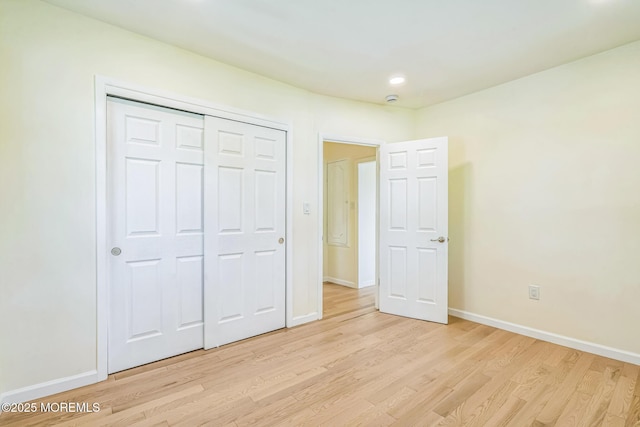unfurnished bedroom with light wood finished floors, a closet, recessed lighting, and baseboards