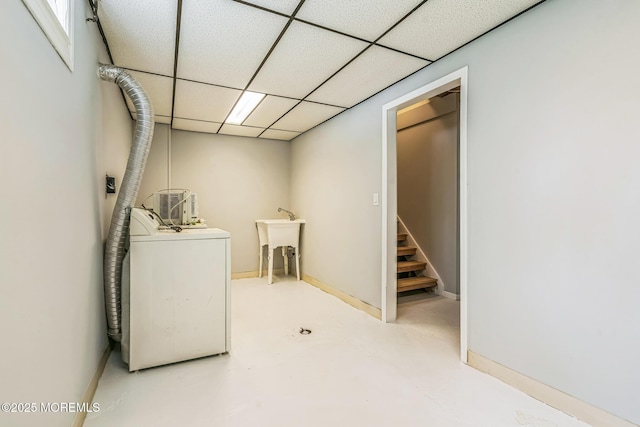 clothes washing area featuring baseboards, washer / clothes dryer, laundry area, and a sink