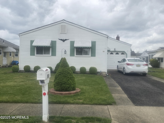 view of front of home with a garage, a chimney, driveway, and a front yard