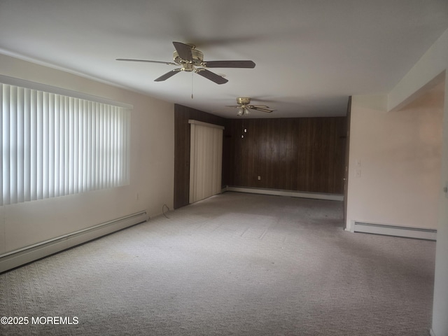 carpeted empty room with baseboard heating, wood walls, ceiling fan, and a baseboard radiator