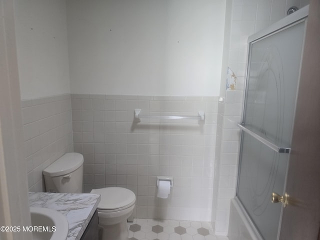 full bath with tile walls, an enclosed shower, and vanity