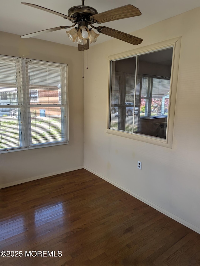 unfurnished room with dark wood-type flooring, ceiling fan, and baseboards