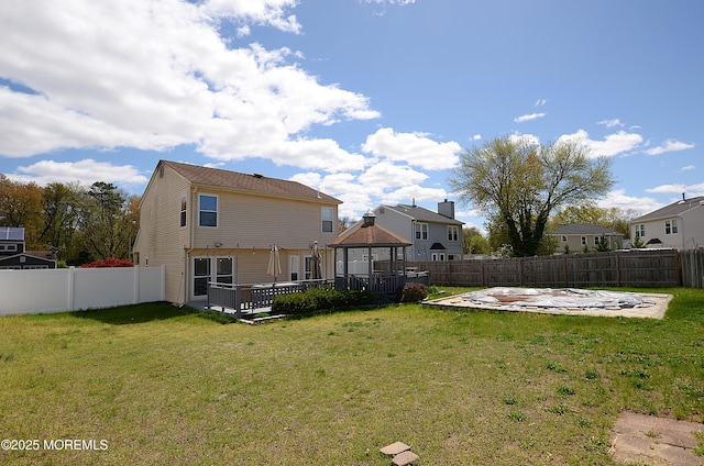 rear view of house featuring a gazebo, a fenced backyard, a lawn, and a deck