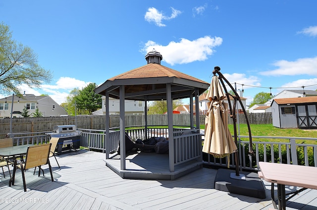 deck with a gazebo, an outdoor structure, a fenced backyard, a shed, and outdoor dining space