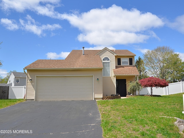 traditional-style home featuring fence, an attached garage, a front yard, and aphalt driveway