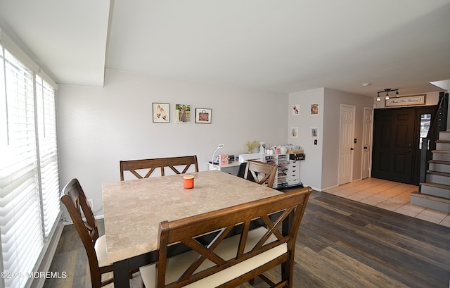 dining area with baseboards, wood finished floors, and stairway