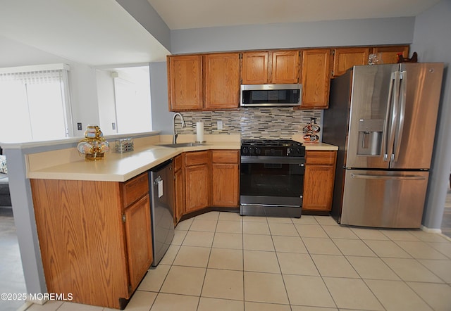 kitchen featuring a peninsula, light countertops, brown cabinets, a sink, and appliances with stainless steel finishes