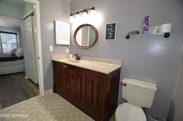 bathroom with toilet, baseboards, and vanity