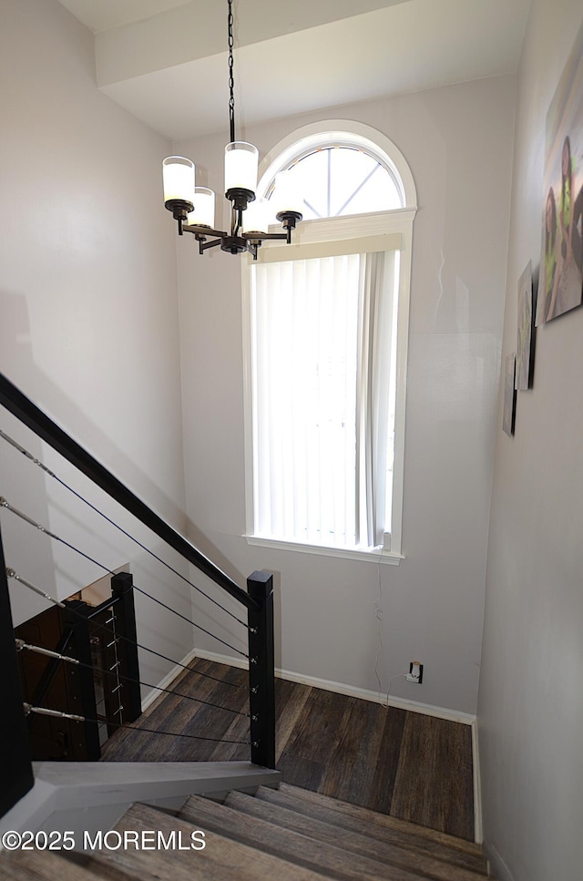 stairs with baseboards, a wealth of natural light, wood finished floors, and a chandelier