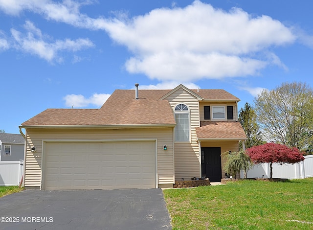 view of front of home featuring an attached garage, fence, driveway, and a front yard