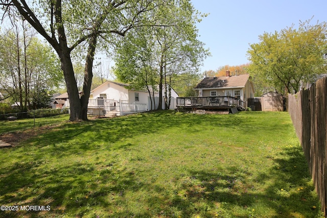 view of yard featuring a storage shed, a deck, an outbuilding, and a fenced backyard