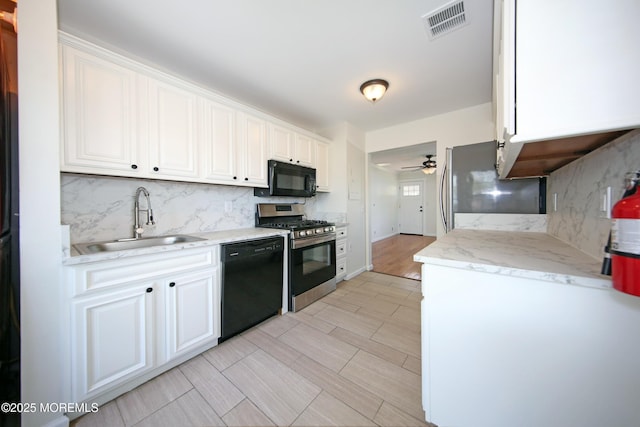 kitchen with a sink, visible vents, ceiling fan, black appliances, and backsplash